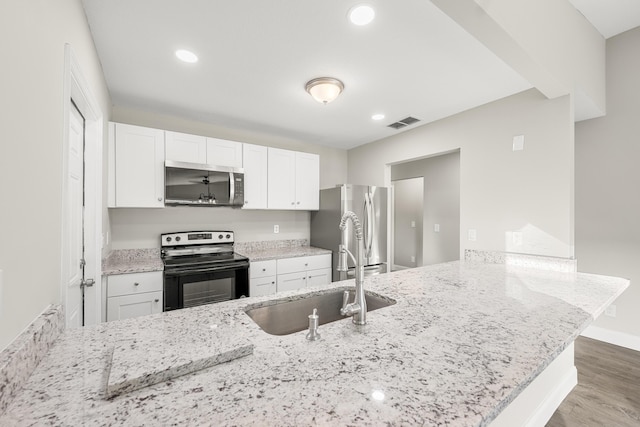 kitchen featuring appliances with stainless steel finishes, white cabinets, kitchen peninsula, and sink