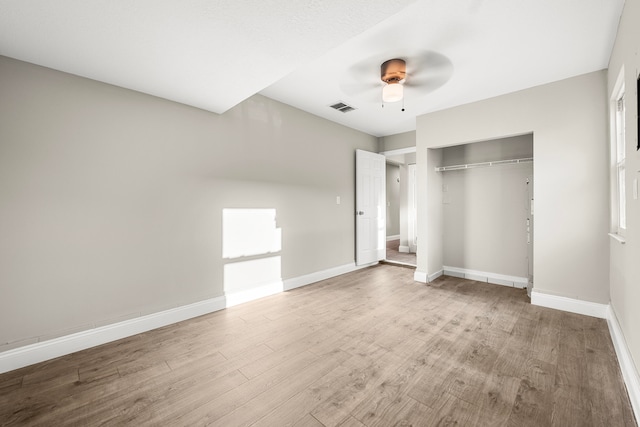 unfurnished bedroom with ceiling fan, a closet, and wood-type flooring