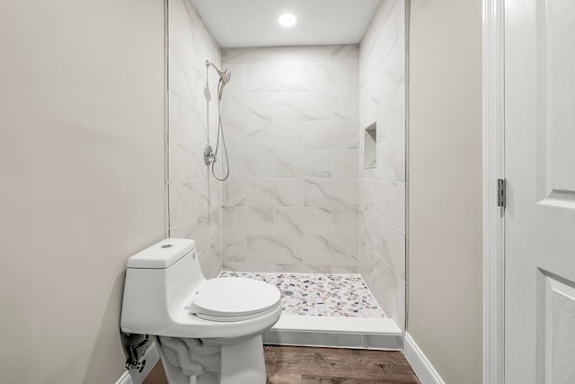 bathroom with toilet, tiled shower, and hardwood / wood-style floors