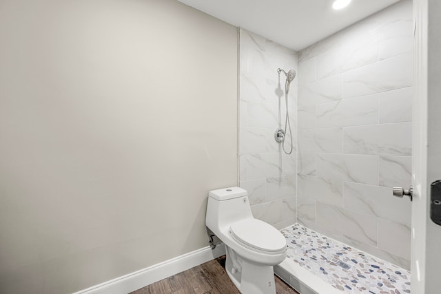 bathroom with hardwood / wood-style floors, toilet, and tiled shower