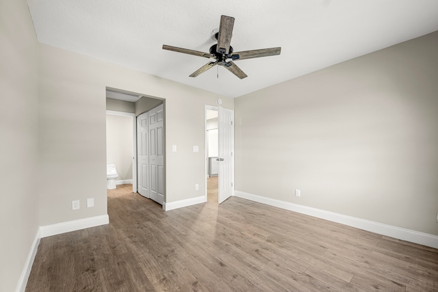 unfurnished bedroom with ceiling fan, connected bathroom, and hardwood / wood-style floors