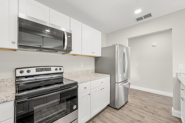 kitchen featuring appliances with stainless steel finishes, white cabinetry, and light stone counters