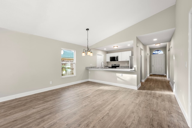 kitchen featuring white cabinetry, kitchen peninsula, electric range, decorative light fixtures, and sink