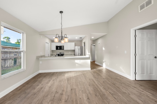 kitchen featuring kitchen peninsula, appliances with stainless steel finishes, lofted ceiling, pendant lighting, and white cabinets