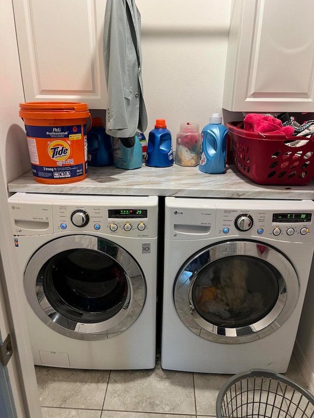 laundry room with cabinets, washing machine and clothes dryer, and light tile patterned floors