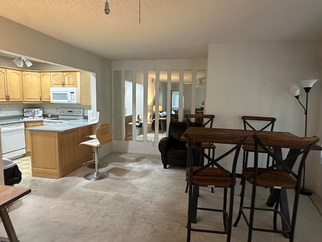 kitchen featuring a center island, white appliances, a kitchen breakfast bar, a textured ceiling, and light colored carpet