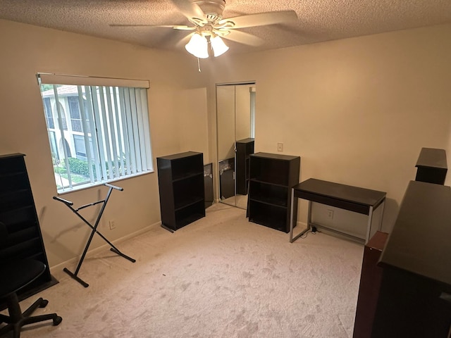 office space featuring ceiling fan, light colored carpet, and a textured ceiling