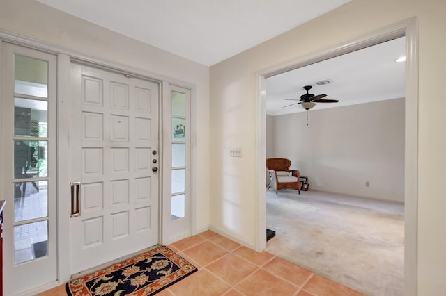 carpeted entrance foyer with ceiling fan and a wealth of natural light