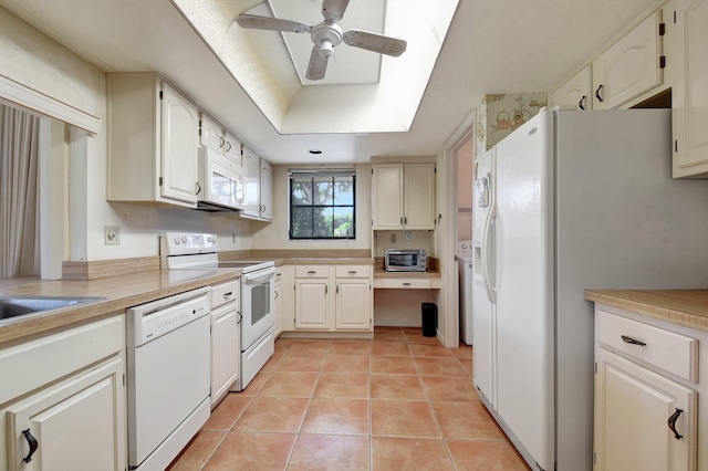 kitchen with white appliances, a raised ceiling, ceiling fan, white cabinets, and light tile patterned flooring