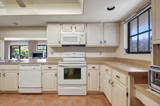 kitchen with kitchen peninsula, sink, light tile patterned floors, and white appliances