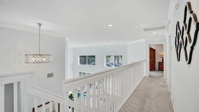 hall with light carpet, a textured ceiling, and ornamental molding