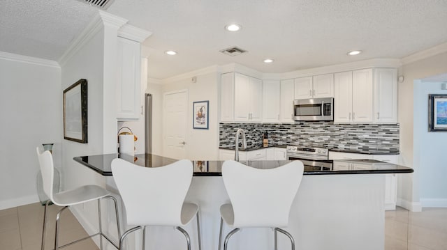 kitchen with stainless steel appliances, kitchen peninsula, crown molding, a textured ceiling, and white cabinets