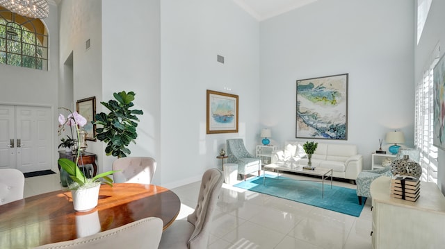 interior space featuring a towering ceiling, ornamental molding, and light tile patterned floors