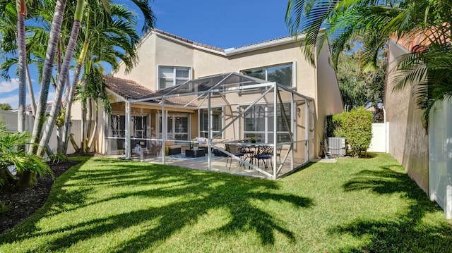 back of property featuring central AC unit, glass enclosure, a patio area, and a yard