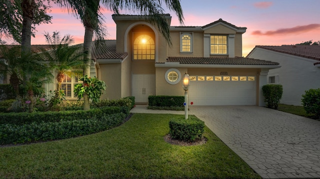 mediterranean / spanish house featuring a garage and a yard