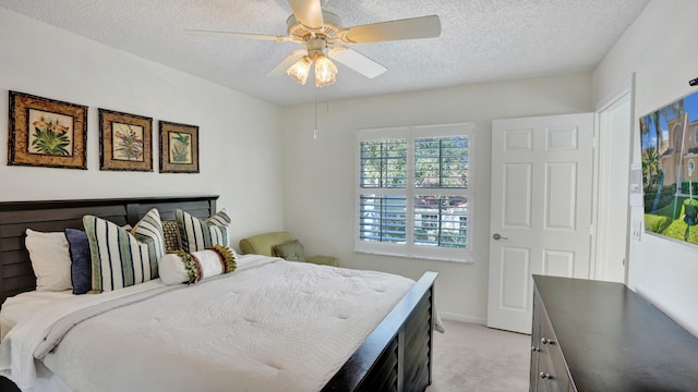 carpeted bedroom featuring ceiling fan and a textured ceiling