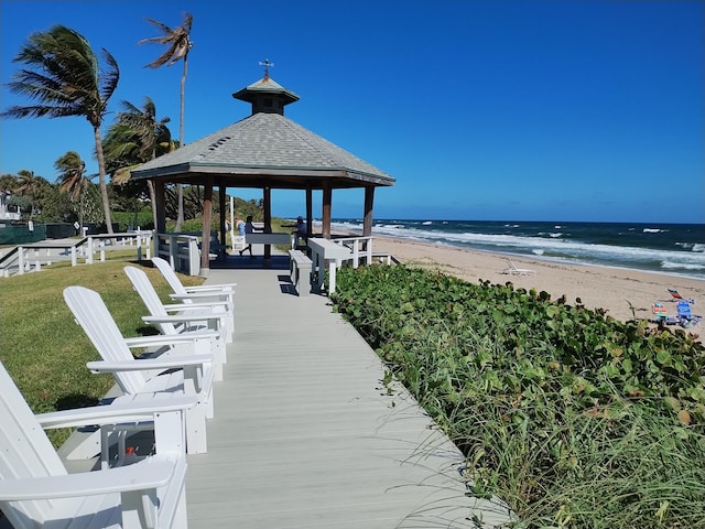 dock area featuring a water view, a yard, a beach view, and a gazebo