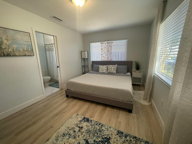 bedroom with ensuite bathroom and light hardwood / wood-style floors