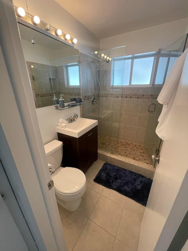 bathroom featuring toilet, tile patterned flooring, vanity, and a shower with door