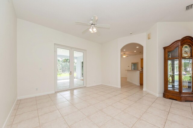 empty room with ceiling fan, light tile patterned floors, and french doors