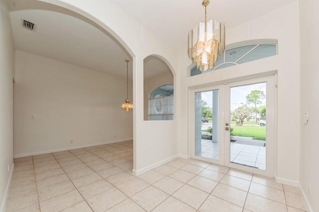 entrance foyer with light tile patterned floors, french doors, and a notable chandelier