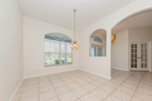 tiled empty room with french doors and an inviting chandelier