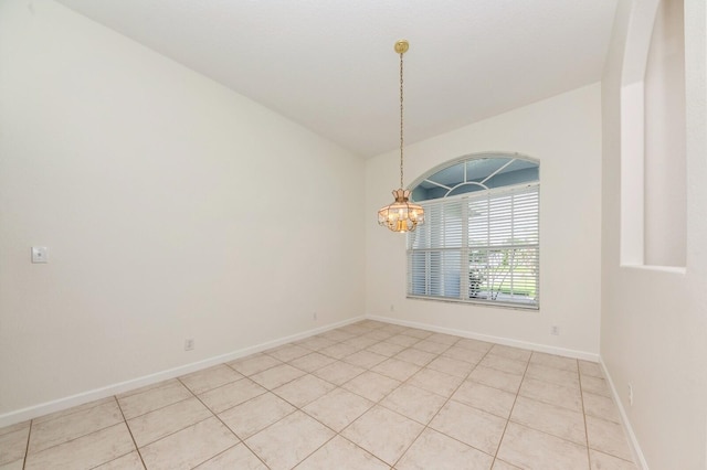 empty room with light tile patterned flooring and a chandelier