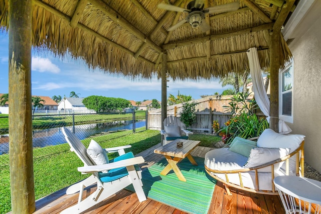 wooden terrace featuring a water view, a lawn, ceiling fan, and a gazebo