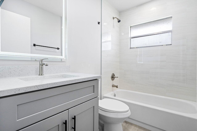 full bathroom featuring tiled shower / bath, vanity, and toilet