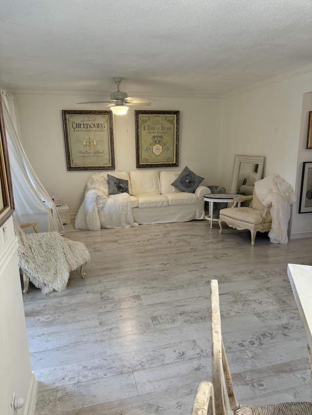 bedroom featuring a ceiling fan, a textured ceiling, ornamental molding, and wood finished floors