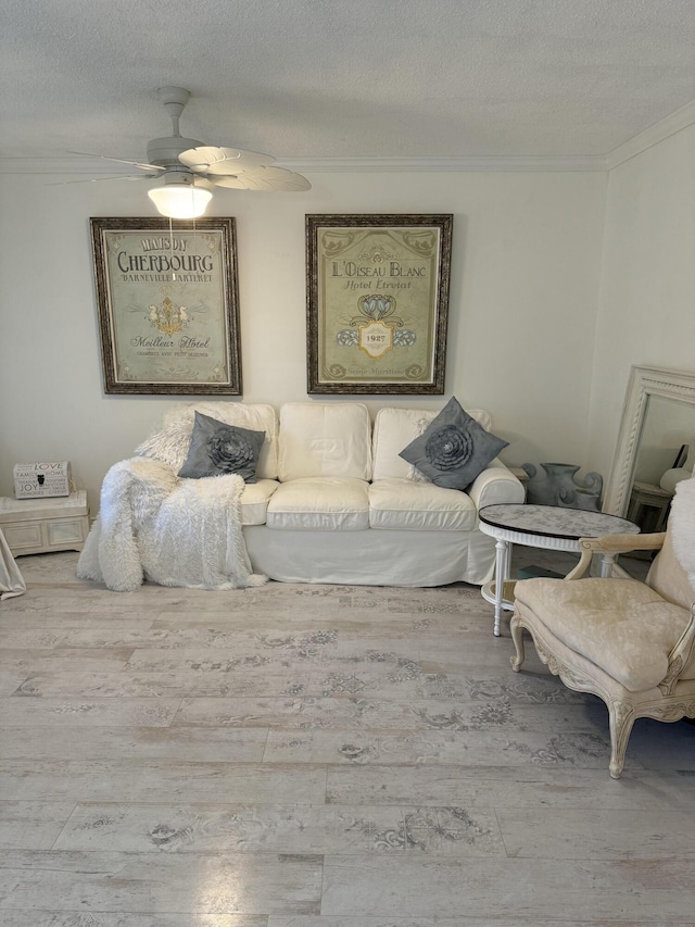 living area with ceiling fan, a textured ceiling, crown molding, and wood finished floors