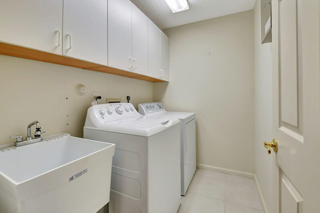 washroom with a textured ceiling, cabinets, sink, and washing machine and clothes dryer