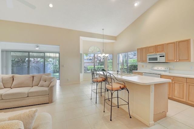 kitchen featuring a kitchen island, a kitchen breakfast bar, sink, pendant lighting, and white appliances