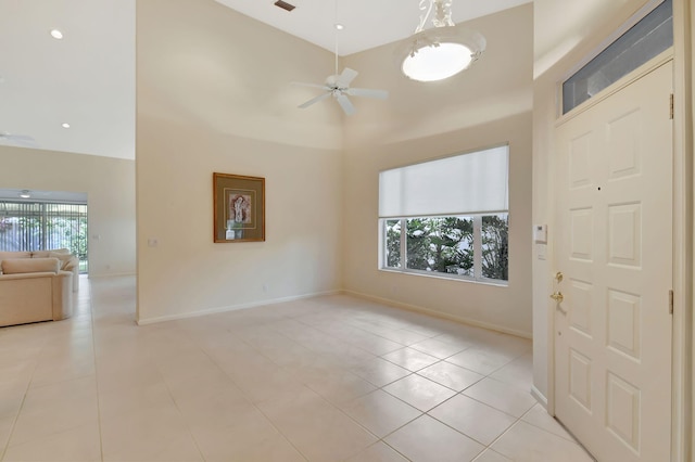 tiled spare room featuring ceiling fan and a high ceiling