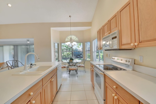 kitchen with white appliances, sink, hanging light fixtures, light tile patterned floors, and an inviting chandelier