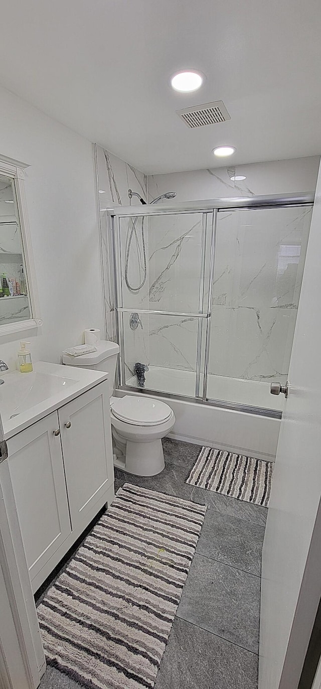 full bathroom with bath / shower combo with glass door, vanity, toilet, and tile patterned floors