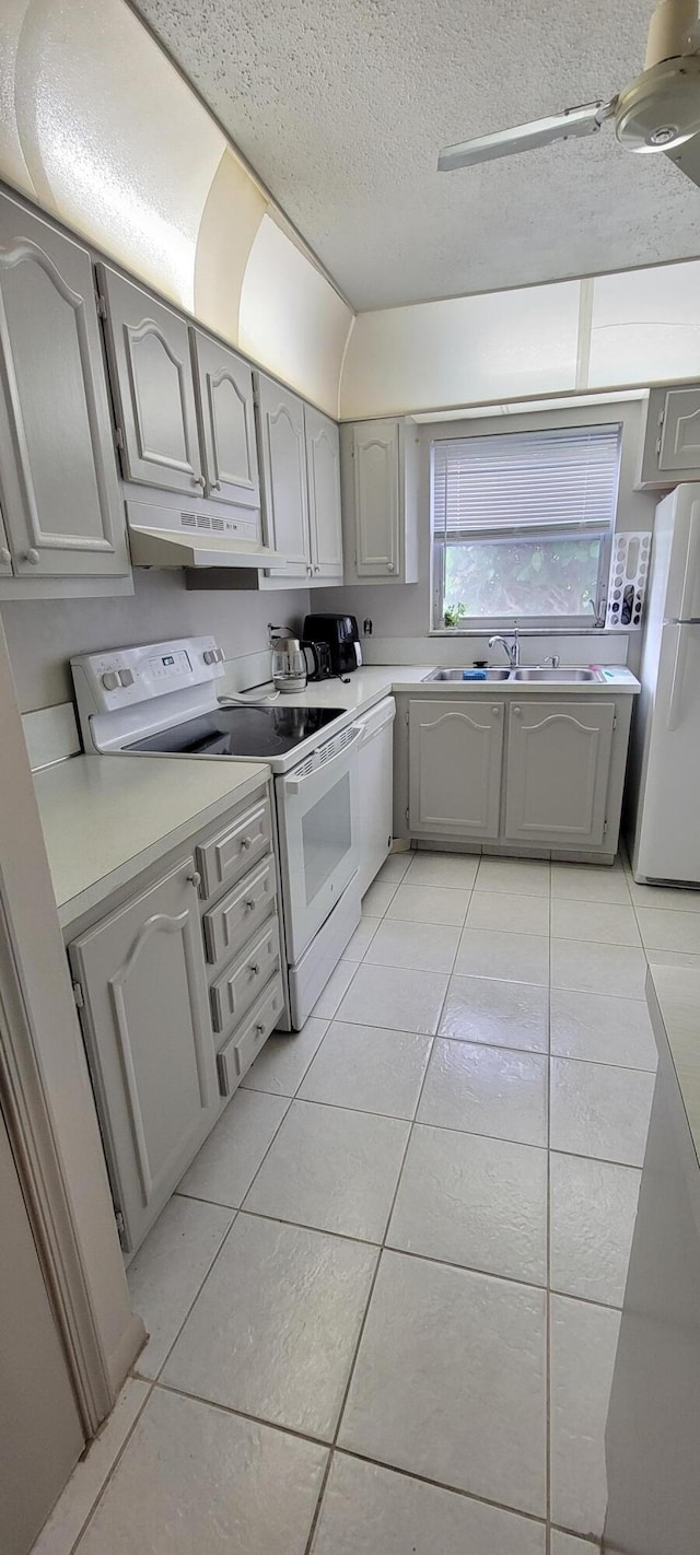 kitchen with white appliances, a textured ceiling, light tile patterned flooring, and gray cabinets