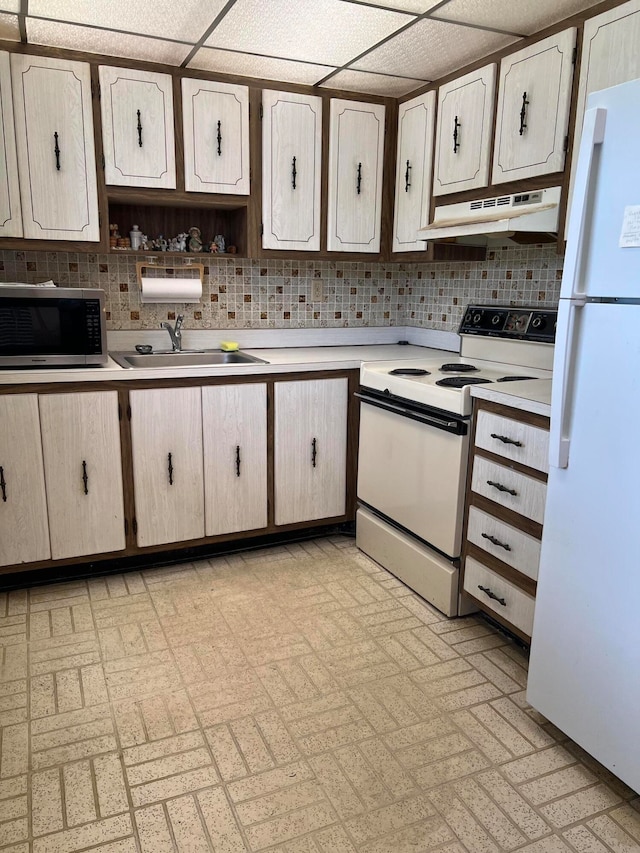 kitchen with white appliances, tasteful backsplash, sink, and a drop ceiling