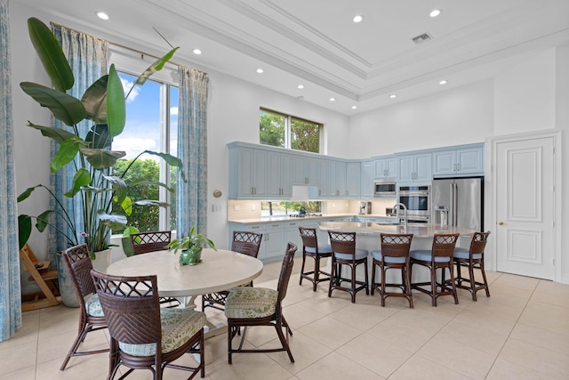 tiled dining space featuring sink, a towering ceiling, and ornamental molding