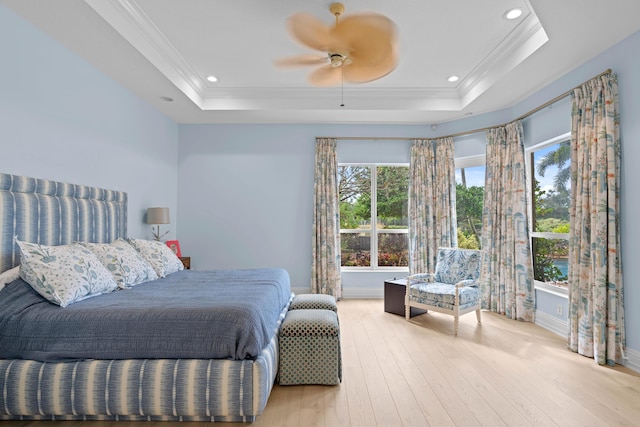 bedroom with ceiling fan, a tray ceiling, light hardwood / wood-style flooring, and crown molding