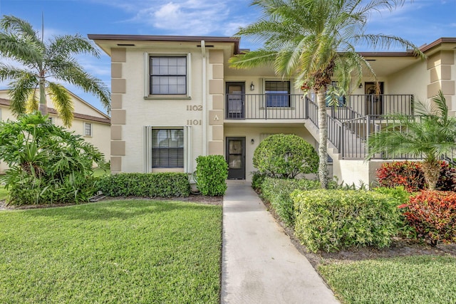 view of front of property featuring a front yard and a balcony