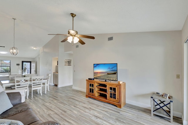 living room with light hardwood / wood-style flooring, high vaulted ceiling, and ceiling fan with notable chandelier