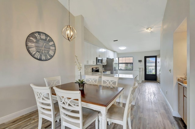 dining area featuring lofted ceiling, a chandelier, and light hardwood / wood-style flooring