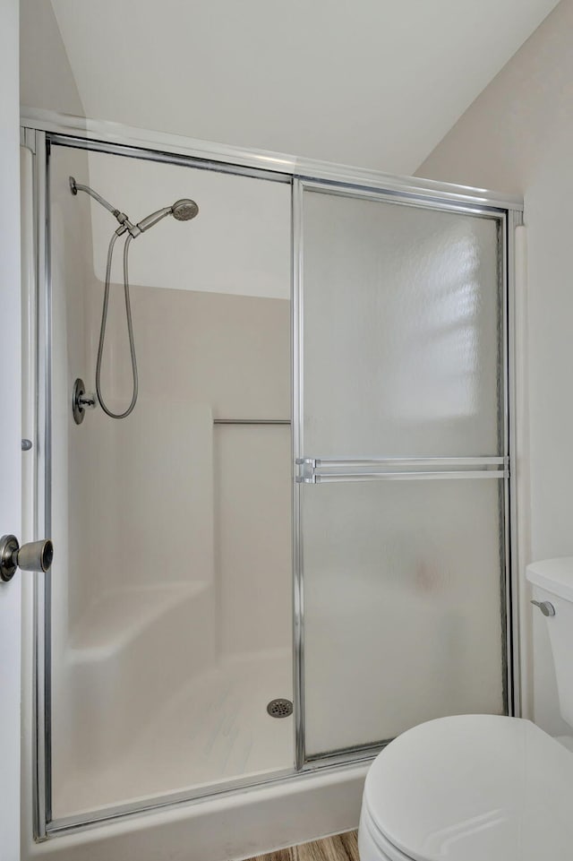 bathroom with a shower with door, hardwood / wood-style flooring, and toilet