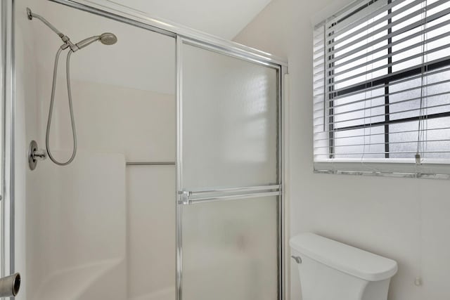 bathroom with toilet, an enclosed shower, and plenty of natural light