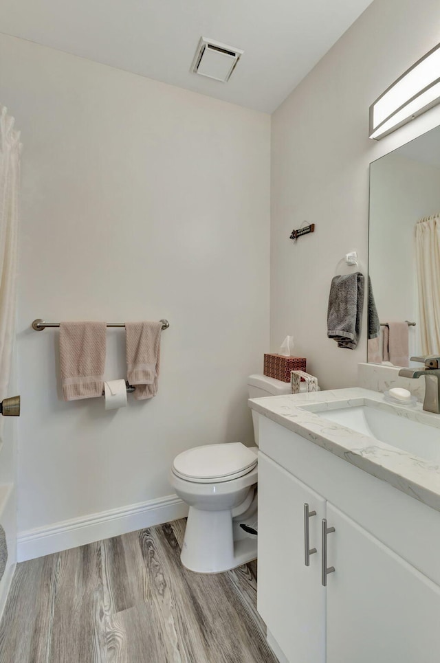 bathroom featuring vanity, a shower with shower curtain, hardwood / wood-style flooring, and toilet