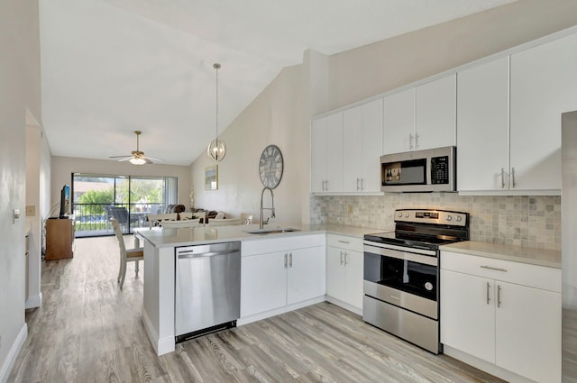 kitchen with appliances with stainless steel finishes, sink, kitchen peninsula, decorative light fixtures, and white cabinets