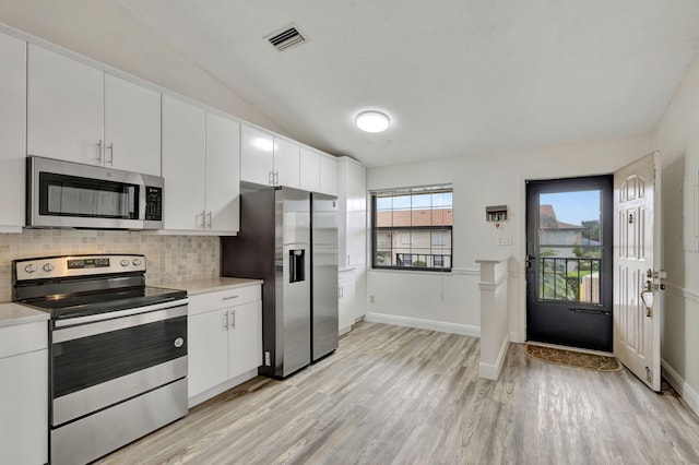 kitchen featuring backsplash, white cabinetry, stainless steel appliances, lofted ceiling, and light hardwood / wood-style flooring