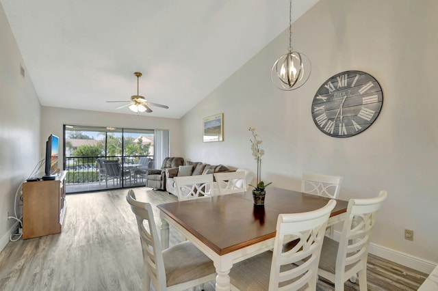 dining space with high vaulted ceiling, wood-type flooring, and ceiling fan with notable chandelier