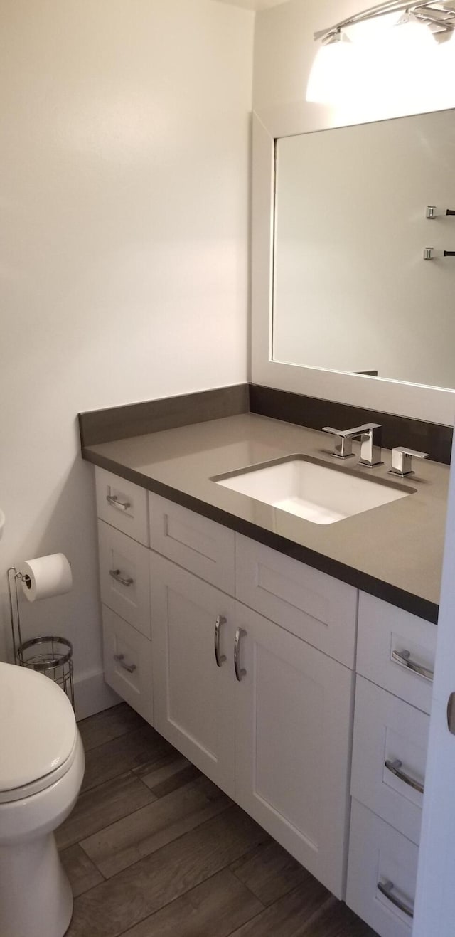 bathroom featuring vanity, hardwood / wood-style flooring, and toilet